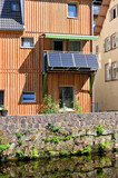 Fototapeta  - Wohnhaus mit Holzfassade am Wasser mit Balkonkraftwerk