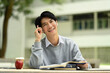 © Prathankarnpap - Asian male student sitting at table outdoor with textbooks, planning working process or thinking about project