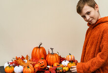 Smiling Boy Arranging Autumnal Halloween Pumpkin Decorations For A Centre Piece