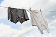 A leaky tank top and underpants hang on a clothesline against a sky of clouds, a concept on the subject of poverty