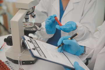 Health care researchers working in life science laboratory. Young female research scientist and senior male supervisor preparing and analyzing microscope slides in research lab.