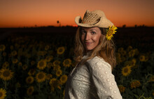 Smiling Woman In Straw Hat Standing In Sunflower Field