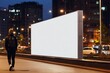 © gankevstock - person looking at blank LED billboard mockup in night city