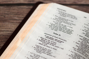 Assurance of God's protection, psalm 61 in open holy bible book on wooden table. Christian encouragement, hope, and peace concept.