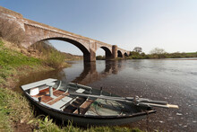 A Boat Along The Shoreline Beside A Bridge In River Tweed; Scottish Borders Scotland