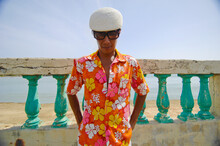 Asian Man In Bright Flowered Shirt In Front Of Wall And Ocean; Puerto Rico