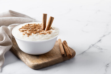 Wall Mural - Arroz con leche. Rice pudding with cinnamon in bowl on white marble. Copy space