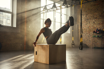 Wall Mural - Working hard. Side view of athletic woman in sportswear training legs at gym.