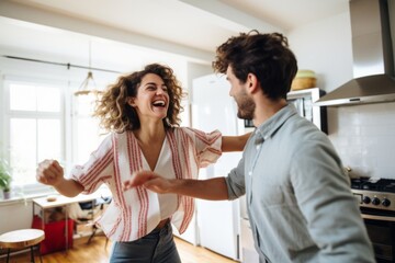 Wall Mural - young couple dancing together in their kitchen happiness joyful marry couple dancing in the kitchen at home weekend sunday morning