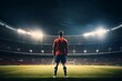 An epic night unfolds at a stadium as a young soccer player, back turned to the camera, stands ready under the spotlight for the kickoff.
