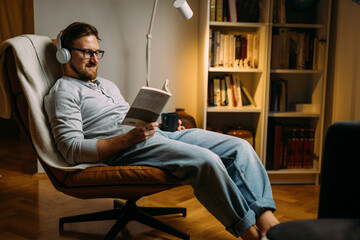 Caucasian man loves relaxing with a good book in the evening at home.