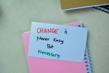 Wall Mural - Concept of Change is Never Easy But Necessary write on sticky notes isolated on Wooden Table.