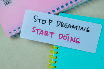 Wall Mural - Concept of Stop Dreaming Start Doing write on sticky notes isolated on Wooden Table.