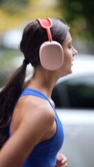 Wall Mural - A cityscape backdrop as a young lady in sportswear and headphones runs by.