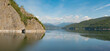 Panorama of lake with reflection of smooth lake surface and cloudy sky. Vidraru dam. Transfagarasan road. Romania