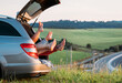 © Soloviova Liudmyla - Four-person family lying in the car trunk and fooling around raising feet up. The young caucasian couple has an auto trip break. Family values, traveling, and friendship concept.