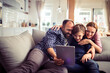 © Geber86 - Young Caucasian family using a tablet and having fun on the couch at home