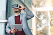 © Dorde - Young stylish man wearing virtual reality headset while holding digital tablet. Young man in VR headset looking away at the objects in virtual reality in front of modern office building.