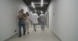 © Framestock - Doctor with male nurse walk the clinic corridor. Colleagues discuss treatment, diagnosis or medical test results. Medical staff and people in hospital or medical center. Healthcare system. Back view.