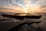 Fototapeta Zachód słońca - Waves on the rocks at the seaside at the sunset