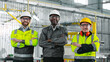 © ihorvsn - Three multicultural heavy industrial workers look at camera and smiling. Engineers standing at construction with crossed arms. Employees in uniforms posing at camera at workshop.