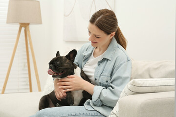 Poster - Happy woman hugging cute French Bulldog on sofa in room