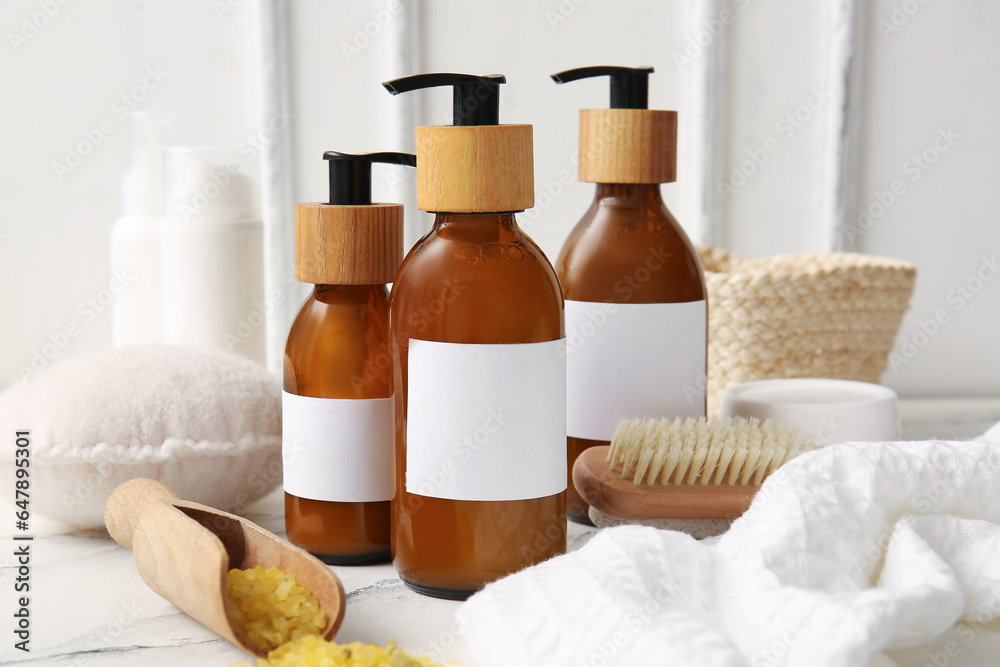 Bottles of shampoo, sea salt and brush on table