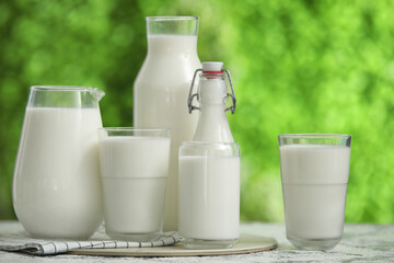 Glasses and bottles of fresh milk on grunge table outdoors