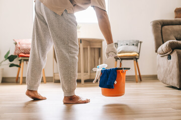 Man hold a bucket of cleaning products ready to clean the room