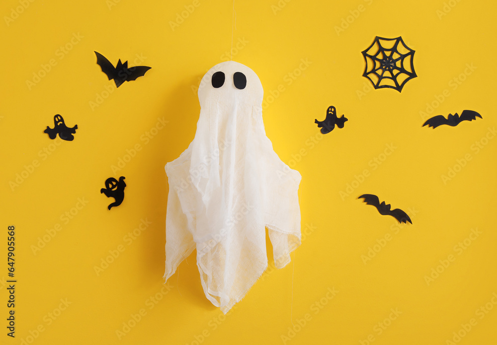 Paper Halloween decor with ghost on yellow wall