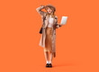 Leinwandbild Motiv Stylish young woman in fall clothes with laptop on orange background