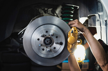 Auto mechanic installing rear brake calipers and disc brake rotors ,car rear brake repair and service. 