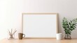 Home office design idea. Mockup of an empty horizontal wooden photo frame. Coffee cup on a wooden table. Background of a white wall. beautiful workspace, vase with olive branches.