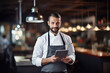© Elaine - Chef holding a tablet looking at the camera in a beautiful modern restaurant