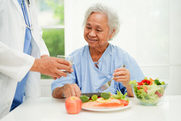 Wall Mural - Asian elderly woman patient eating salmon stake and vegetable salad for healthy food in hospital.