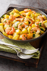 Wall Mural - Roasted potatoes with garlic, herbs and shrimp close-up in a plate on the table. Vertical