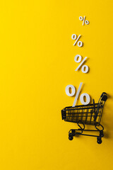 Poster - Shopping trolley and white percent signs with copy space on yellow background