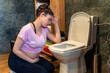 © DusanJelicic - Pregnant woman kneeling on a bathroom floor holding her head up with her hand, she feels sick, she has morning sickness.
