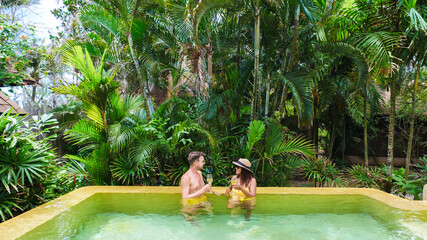 Wall Mural - a couple of men and woman on a luxury vacation in Thailand at a 5 star resort relaxing in the swimming pool of a luxury villa in Thailand