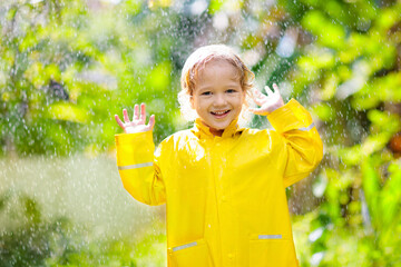 Wall Mural - Child playing in the rain. Kid with umbrella.