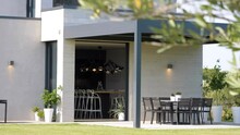 Slow Revealing Shot Of A Modern White Villa With Garden Seating Under A Canopy