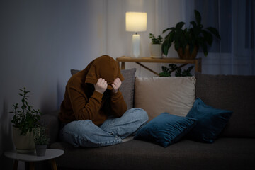 Wall Mural - sad teenager girl sitting on couch indoor at night