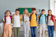 © Studio Romantic - Group of elementary school students standing together in row and hugging. Portrait of happy friends, classmates wearing casual clothes posing in classroom looking at camera. School education concept