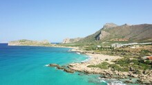 The Sandy Coastline Below The Rocky Cliffs In The Middle Of The Arid Countryside, In Europe, In Greece, In Crete, Towards Kissamos, Towards Chania, By The Mediterranean Sea, In Summer, On A Sunny Day.