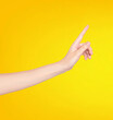 © Robert Kiyosaki - Female hand pointing at something isolated on yellow background with copy space.