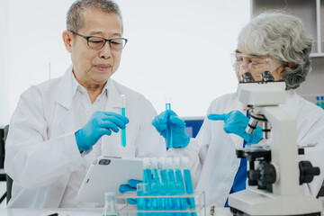 two asian scientists in the laboratory or medical personnel looking at a microscope in the lab