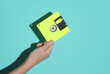 © splitov27 - Hand holding a yellow retro 80s floppy disk on a blue background