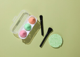 Wall Mural - Makeup brushes and make up sponges on green background. Beauty concept