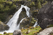 Waterfall Rushing Over Rocks And Splashing Into A River; Olden, Norway