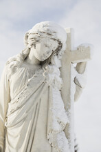 A Tombstone With A Sculpture Of A Girl Holding A Cross In Burnsland Cemetery In Winter; Calgary, Alberta, Canada